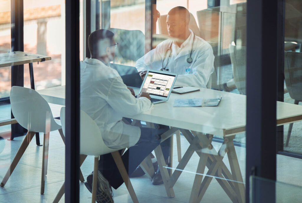 Doctors, men and laptop in hospital meeting for surgery planning, insurance application or medical lab data analysis. Healthcare workers, teamwork or research on technology for science medicine trust.